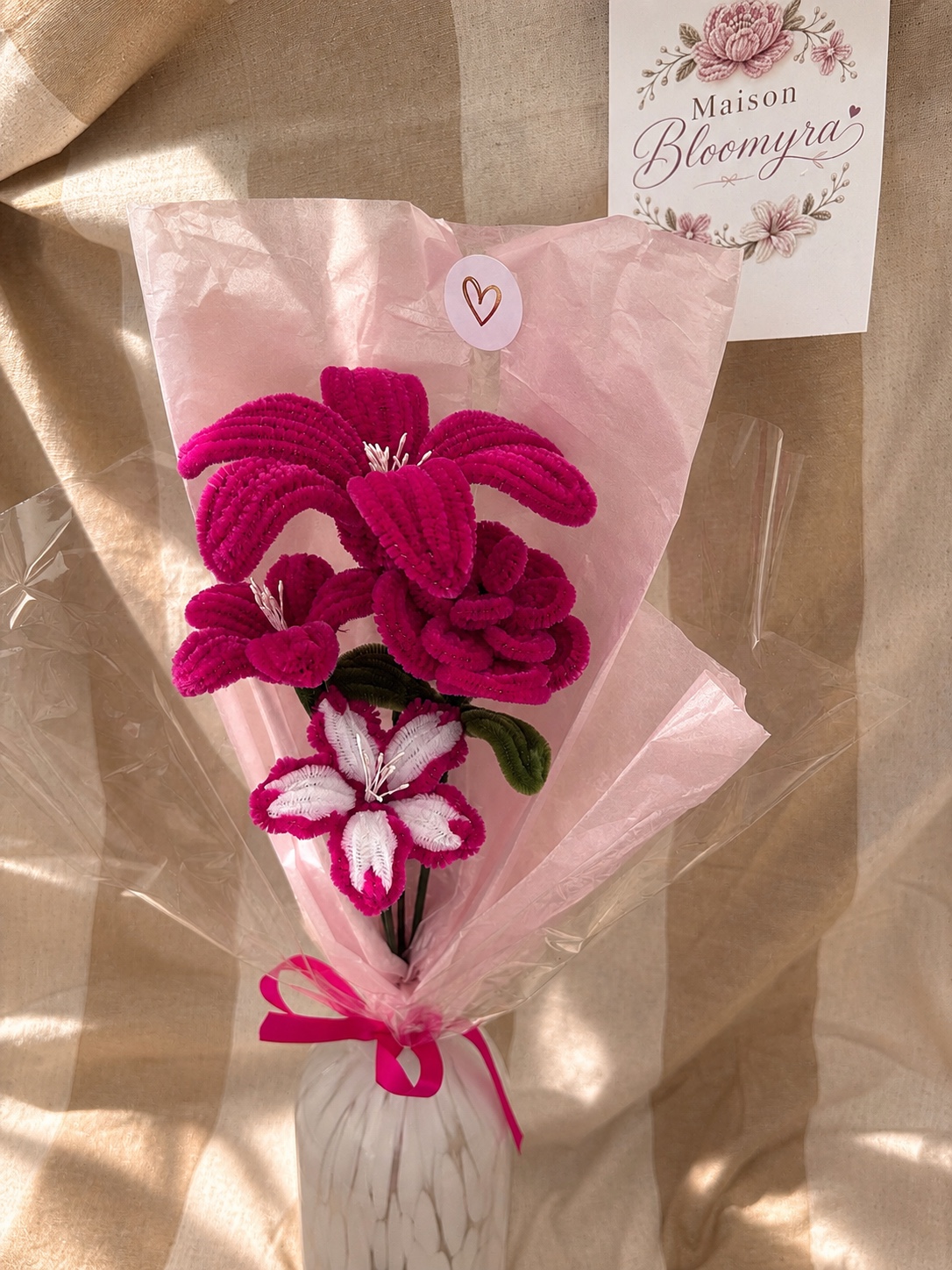 Bouquet Maison Bloomyra en fil chenille rose fuchsia et blanc, emballé de papier rose